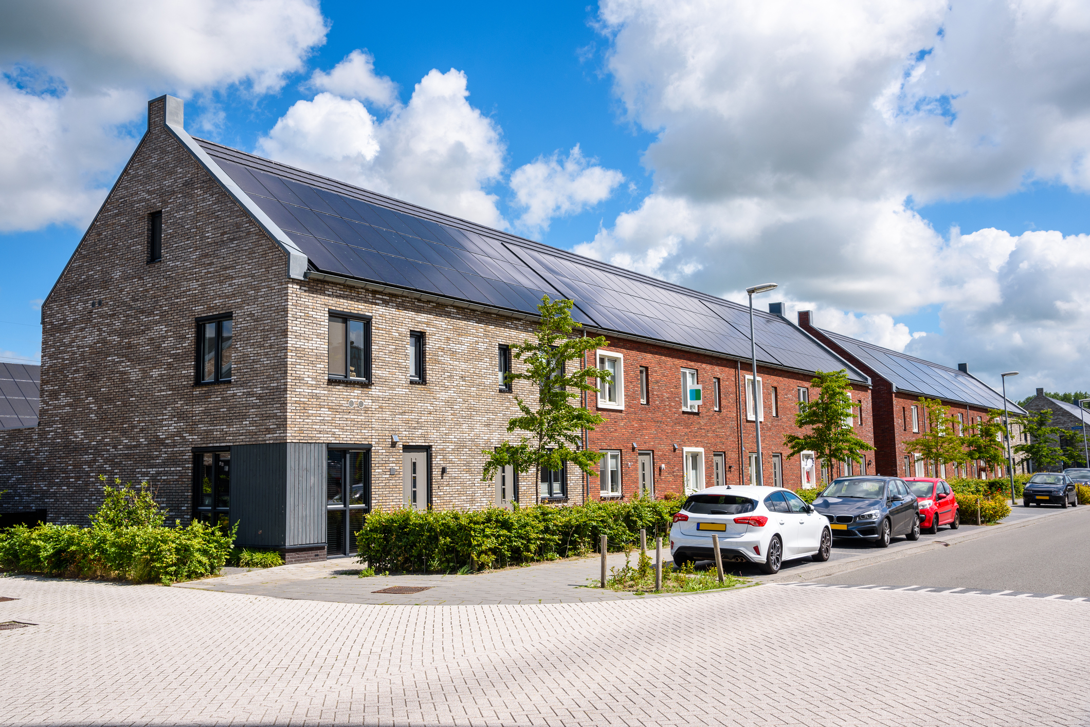 Row of new energy efficient brick terraced houses with the rooftop covered with solar panels on a sunny summer day. Groningen, Netherlands.