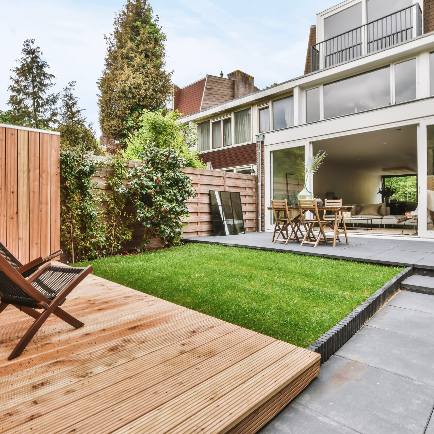 Stylish and well-maintained courtyard of the house with wooden table and chairs Stylish and well-maintained courtyard of the house with wooden table and chairs and a fresh lawn